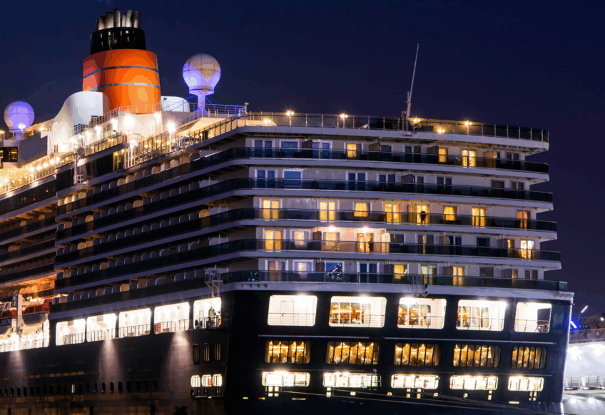 夜の博多港に停泊する大型クルーズ船。ライトアップされた船体が水面に美しく映る様子。